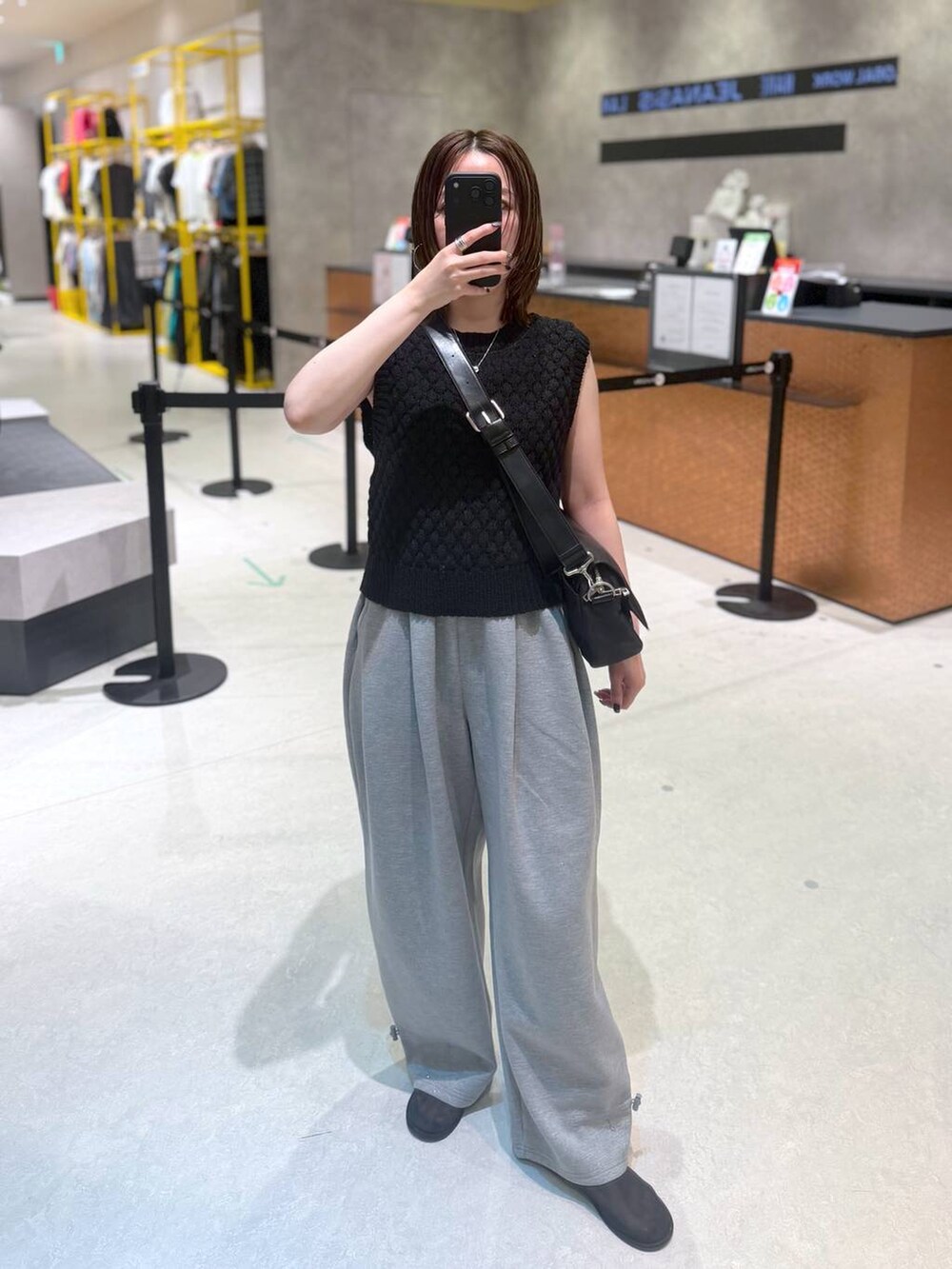 グレー系のスウェットパンツ、ブラック系のベスト、ブラック系のショルダーバッグを着用したレディースの夏コーディネートの3枚目の写真