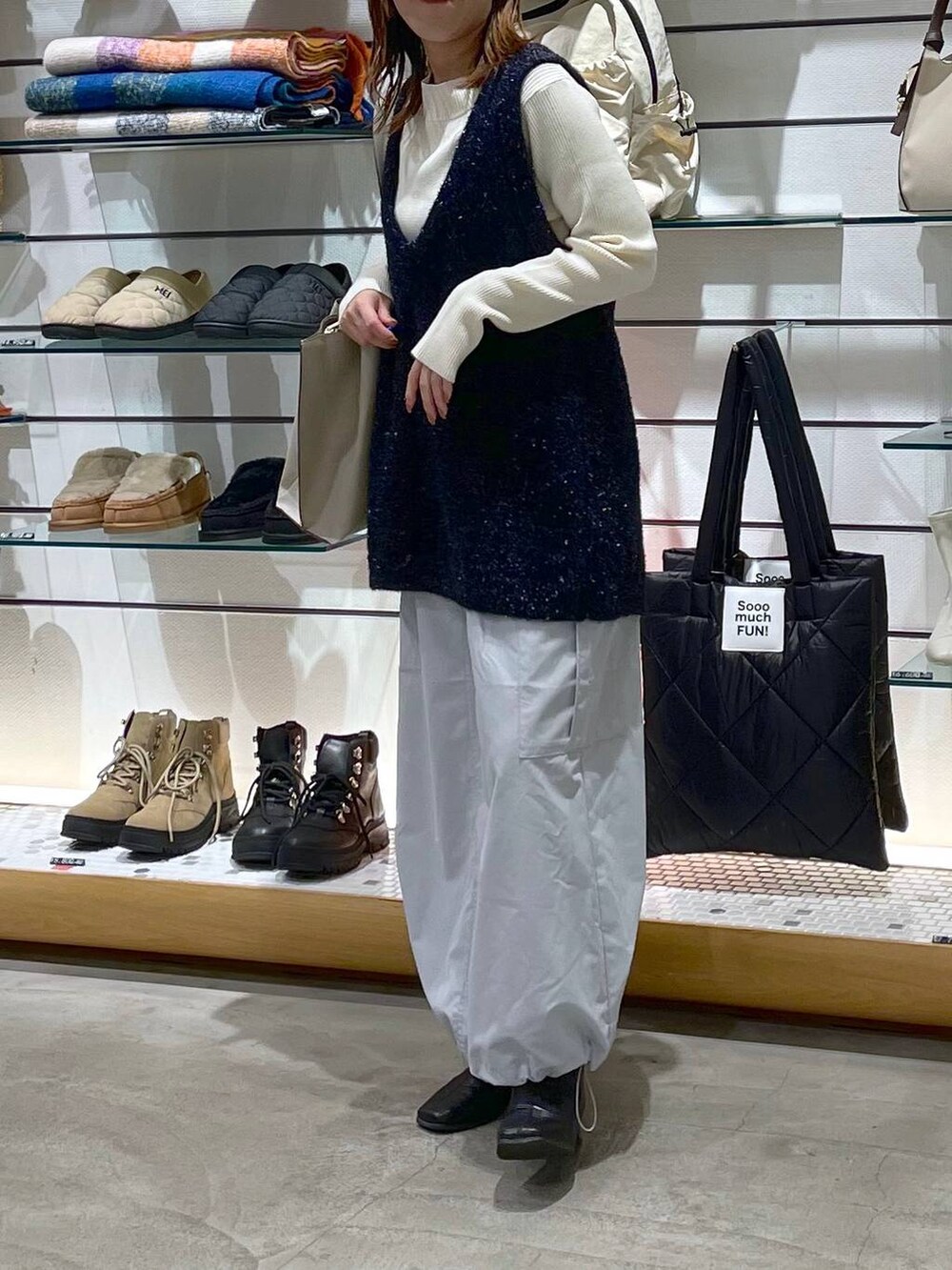 ホワイト系のニット/セーター、グレー系のスカート、ベージュ系のトートバッグを着用したレディースの冬コーディネートの2枚目の写真