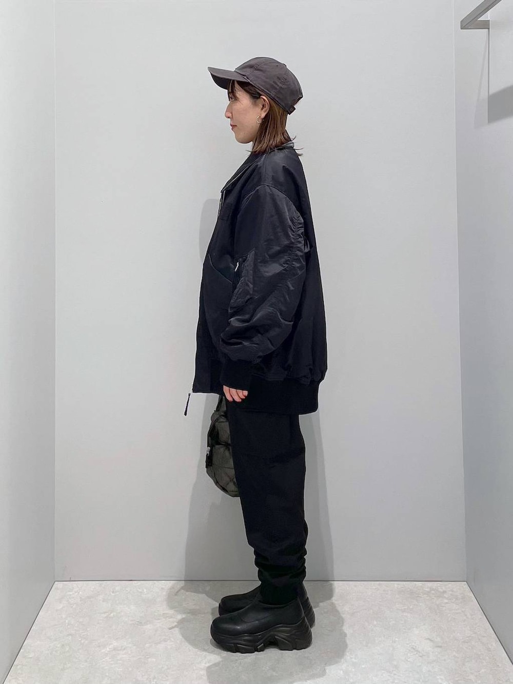 ブラック系のブルゾン、ブラック系のトートバッグ、ブラック系のカーゴパンツを着用したレディースの冬コーディネートの2枚目の写真