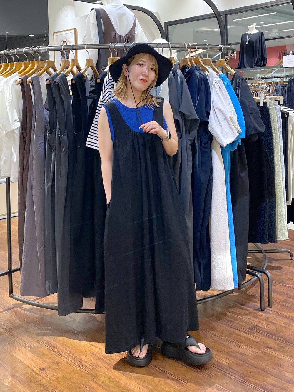 ブラック系のサンダル、ブルー系のタンクトップ、ブラック系のジャンパースカートを着用したレディースの夏コーディネートの3枚目の写真