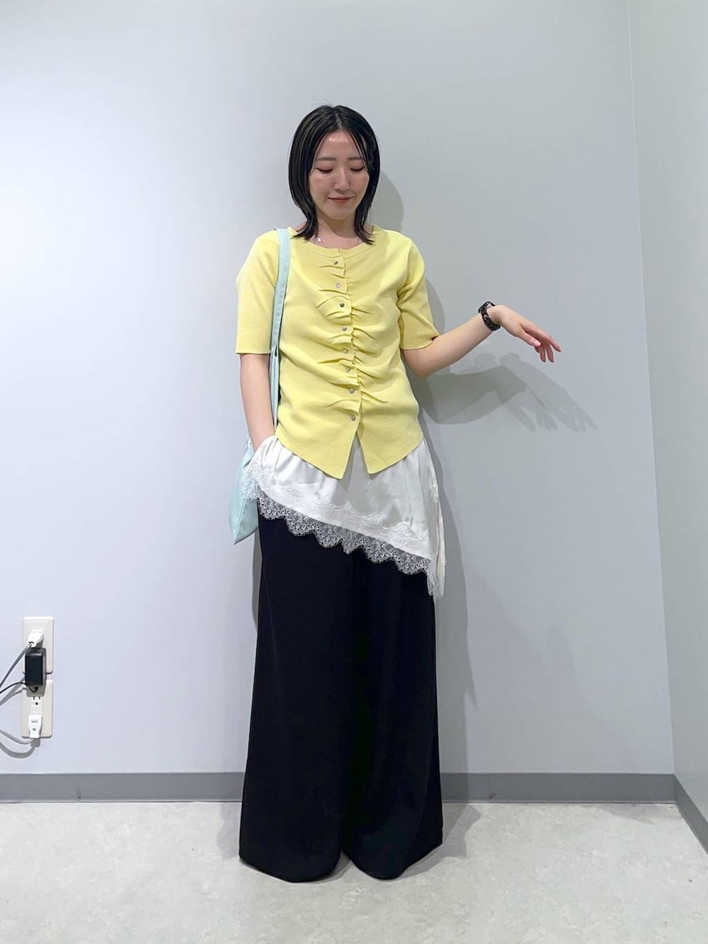 ブラック系のその他パンツ、ホワイト系のキャミソール、イエロー系のカーディガン/ボレロを着用したレディースの春コーディネートの2枚目の写真