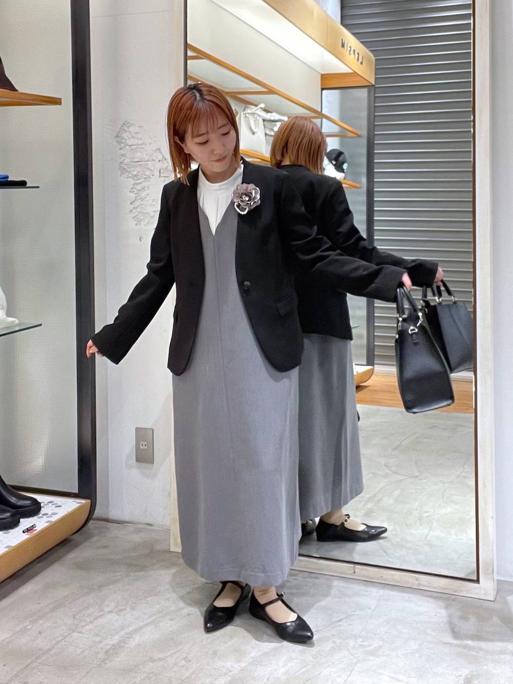 ブラック系のノーカラージャケット、ホワイト系のシャツ/ブラウス、ブラック系のショルダーバッグを着用したレディースの冬コーディネートの2枚目の写真