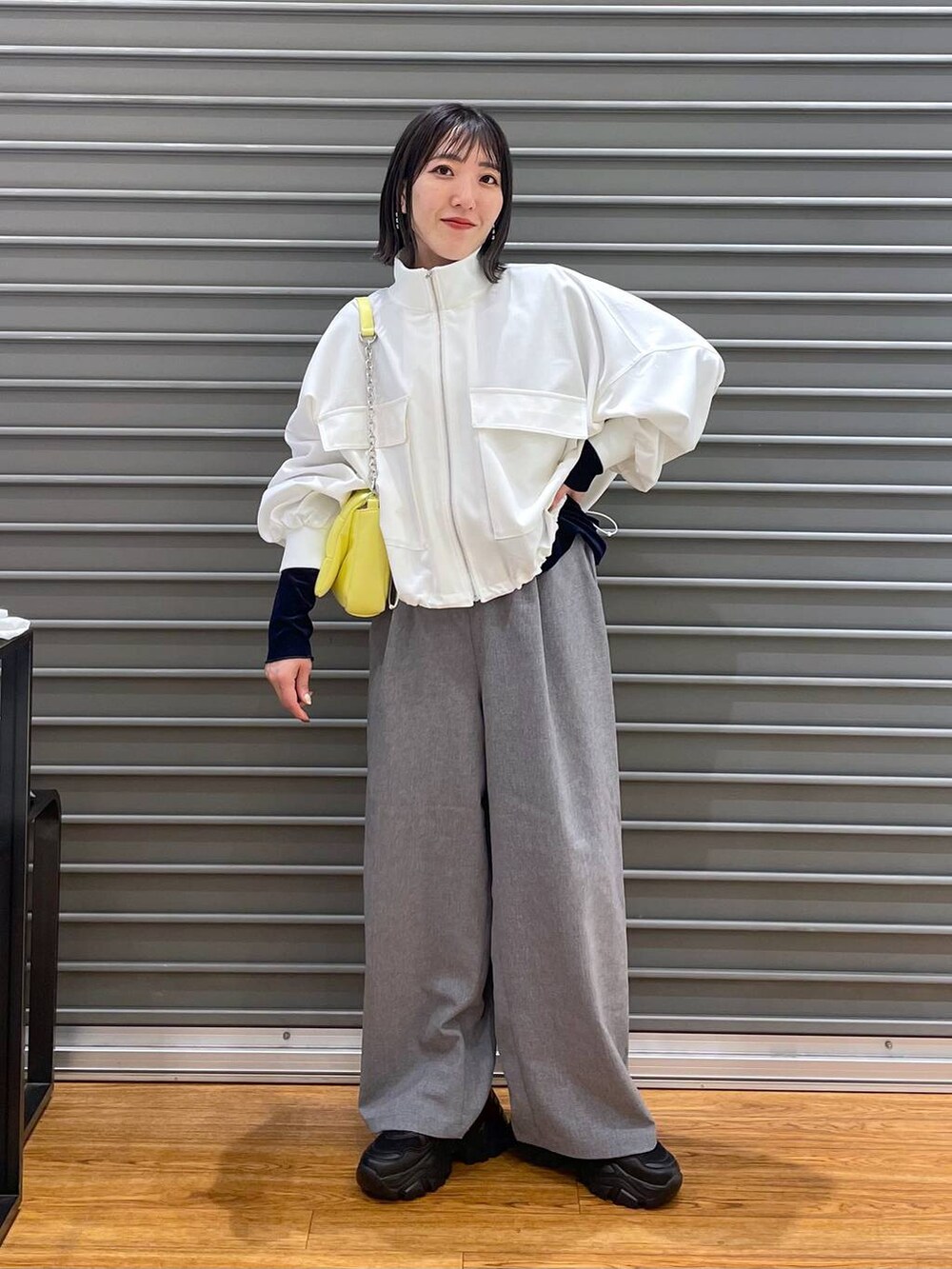 ブルー系のTシャツ/カットソー、イエロー系のショルダーバッグ、グレー系のスラックスを着用したレディースの春コーディネートの3枚目の写真