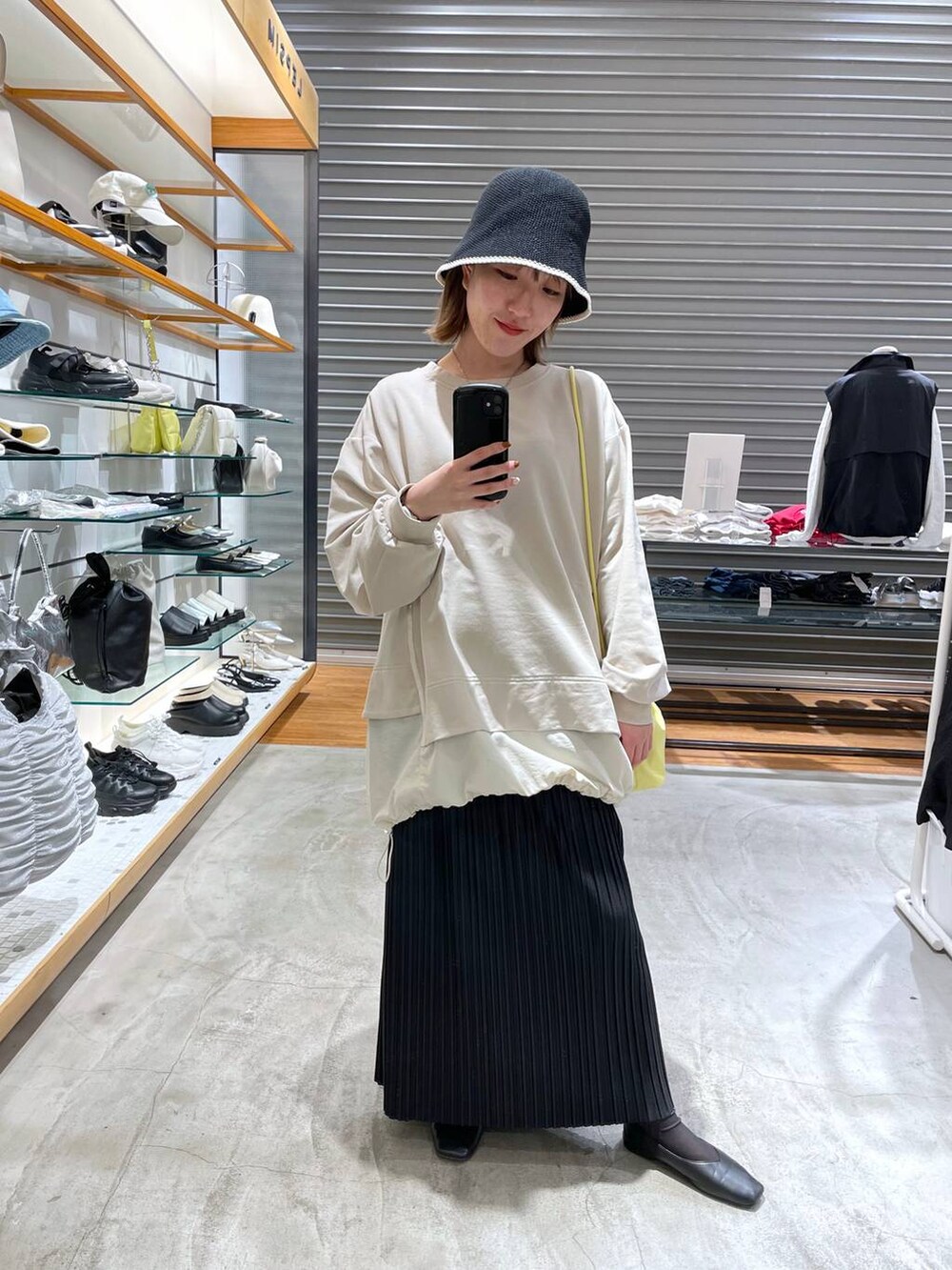 イエロー系のショルダーバッグ、ブラック系のスカート、ベージュ系のTシャツ/カットソーを着用したレディースの春コーディネートの2枚目の写真