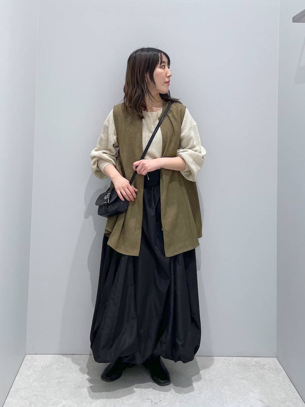 ホワイト系のニット/セーター、ブラウン系のベスト、ブラック系のショルダーバッグを着用したレディースの春コーディネートの4枚目の写真