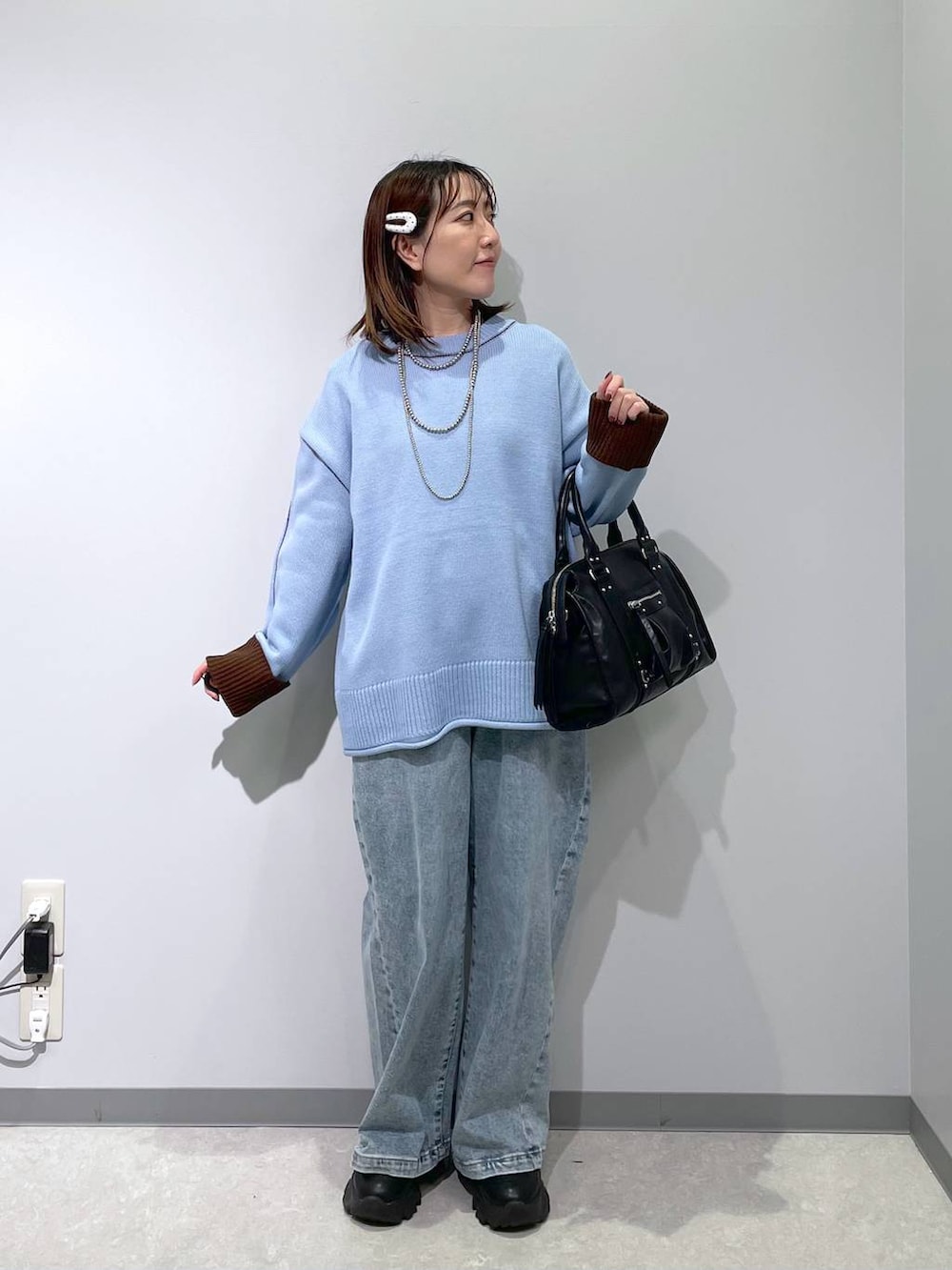 ブラック系のボストンバッグ、ブルー系のデニムパンツ、ブルー系のニット/セーターを着用したレディースの冬コーディネートの4枚目の写真