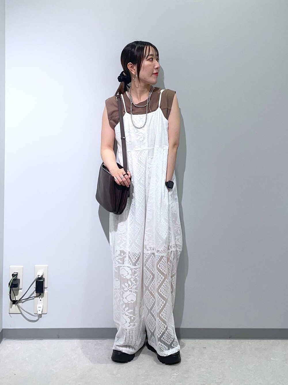 ブラック系のサンダル、ベージュ系のサロペット/オーバーオール、ブラウン系のショルダーバッグを着用したレディースの夏コーディネートの2枚目の写真