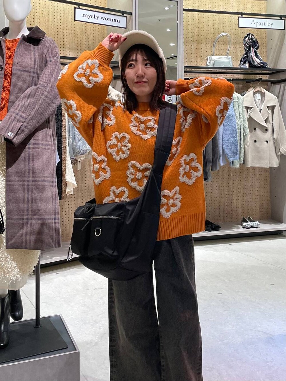 ブラック系のショルダーバッグ、ブラック系のデニムパンツ、オレンジ系のニット/セーターを着用したレディースの冬コーディネートの7枚目の写真