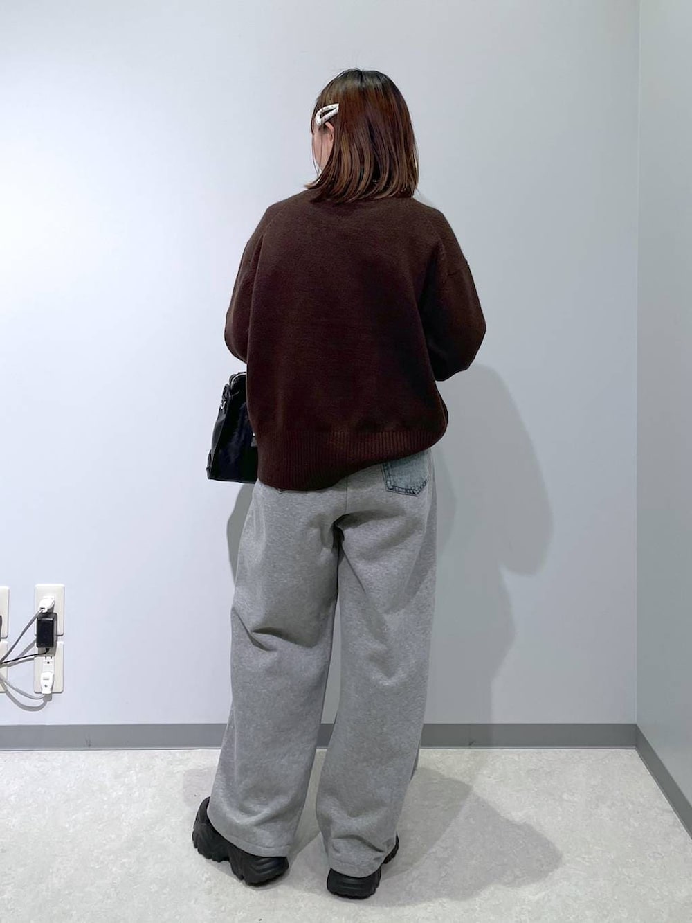 ブラック系のボストンバッグ、ブルー系のデニムパンツ、ブラウン系のニット/セーターを着用したレディースの冬コーディネートの3枚目の写真