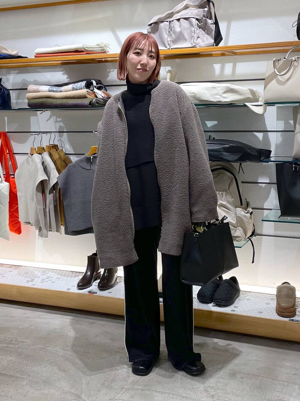 ブラック系のニット/セーター、ブラウン系のノーカラーコート、ブラック系のブーツを着用したレディースの冬コーディネートの2枚目の写真