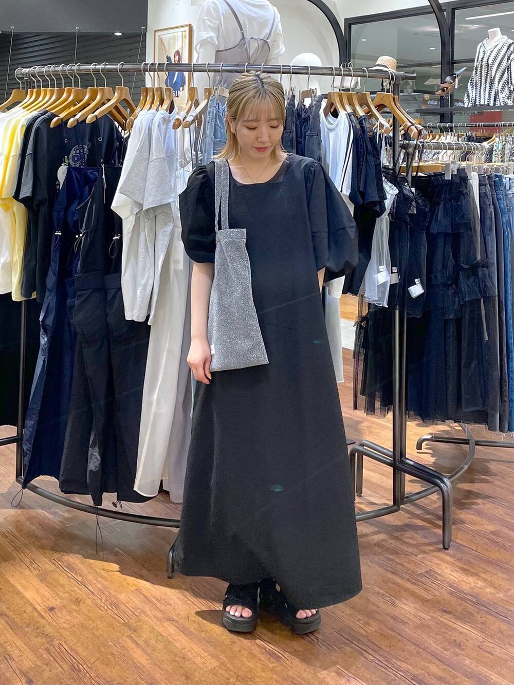 シルバー系のトートバッグ、ブラック系のワンピースを着用したレディースの夏コーディネートの3枚目の写真