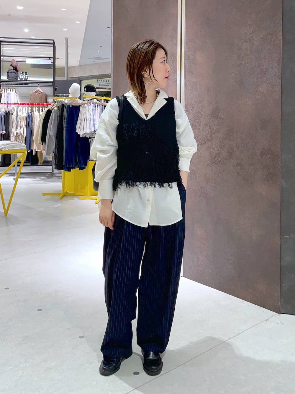 ブラック系のショルダーバッグ、ホワイト系のシャツ/ブラウス、ブラック系のベストを着用したレディースの春コーディネートの3枚目の写真