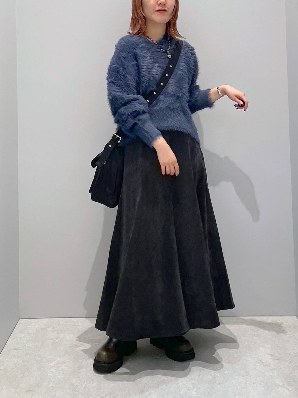 ブラック系のショルダーバッグ、グリーン系のブーツ、ブラック系のスカートを着用したレディースの秋コーディネートの3枚目の写真