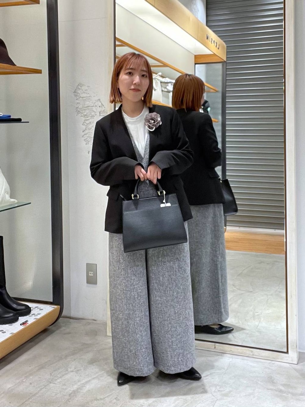 ブラック系のノーカラージャケット、ホワイト系のサロペット/オーバーオール、ホワイト系のシャツ/ブラウスを着用したレディースの冬コーディネートの2枚目の写真