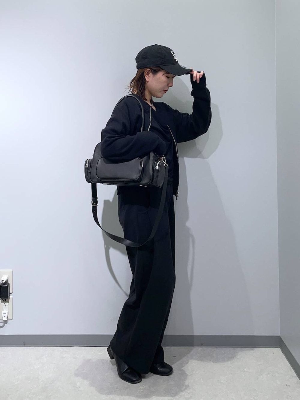 ブラック系のボストンバッグ、ブラック系のTシャツ/カットソー、ブラック系のカーディガン/ボレロを着用したレディースの冬コーディネートの3枚目の写真