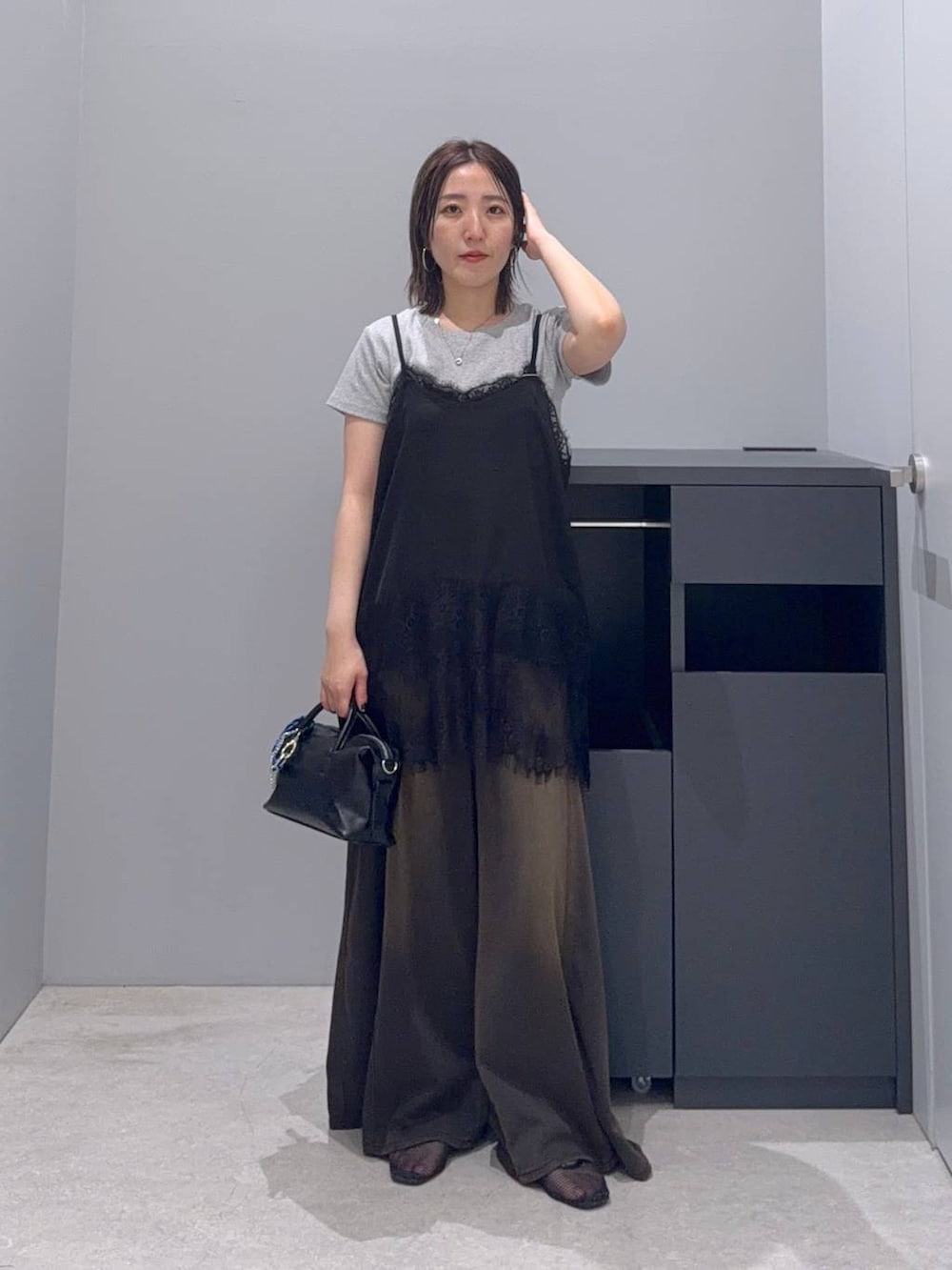 ブラウン系のデニムパンツ、ブラック系のボストンバッグ、ブラック系のTシャツ/カットソーを着用したレディースの夏コーディネートの3枚目の写真