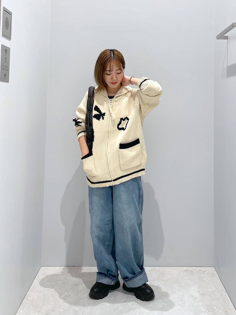 ブルー系のデニムパンツ、ブラック系のハンドバッグ、ベージュ系のカーディガン/ボレロを着用したレディースの秋コーディネートの3枚目の写真