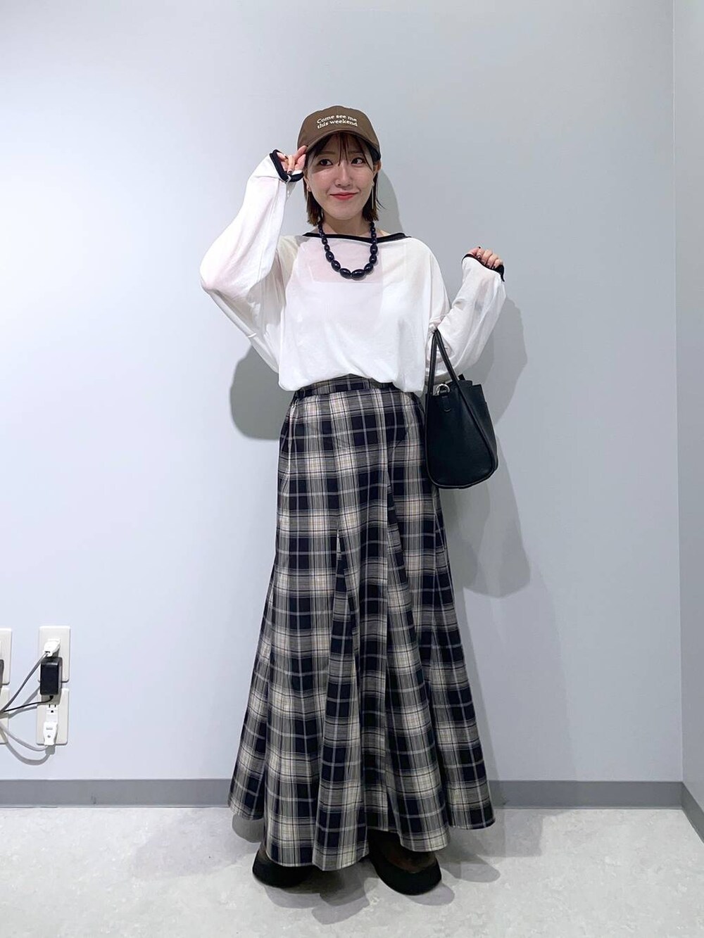 ブラック系のスカート、ブラック系のショルダーバッグ、ブラウン系のサンダルを着用したレディースの秋コーディネートの2枚目の写真