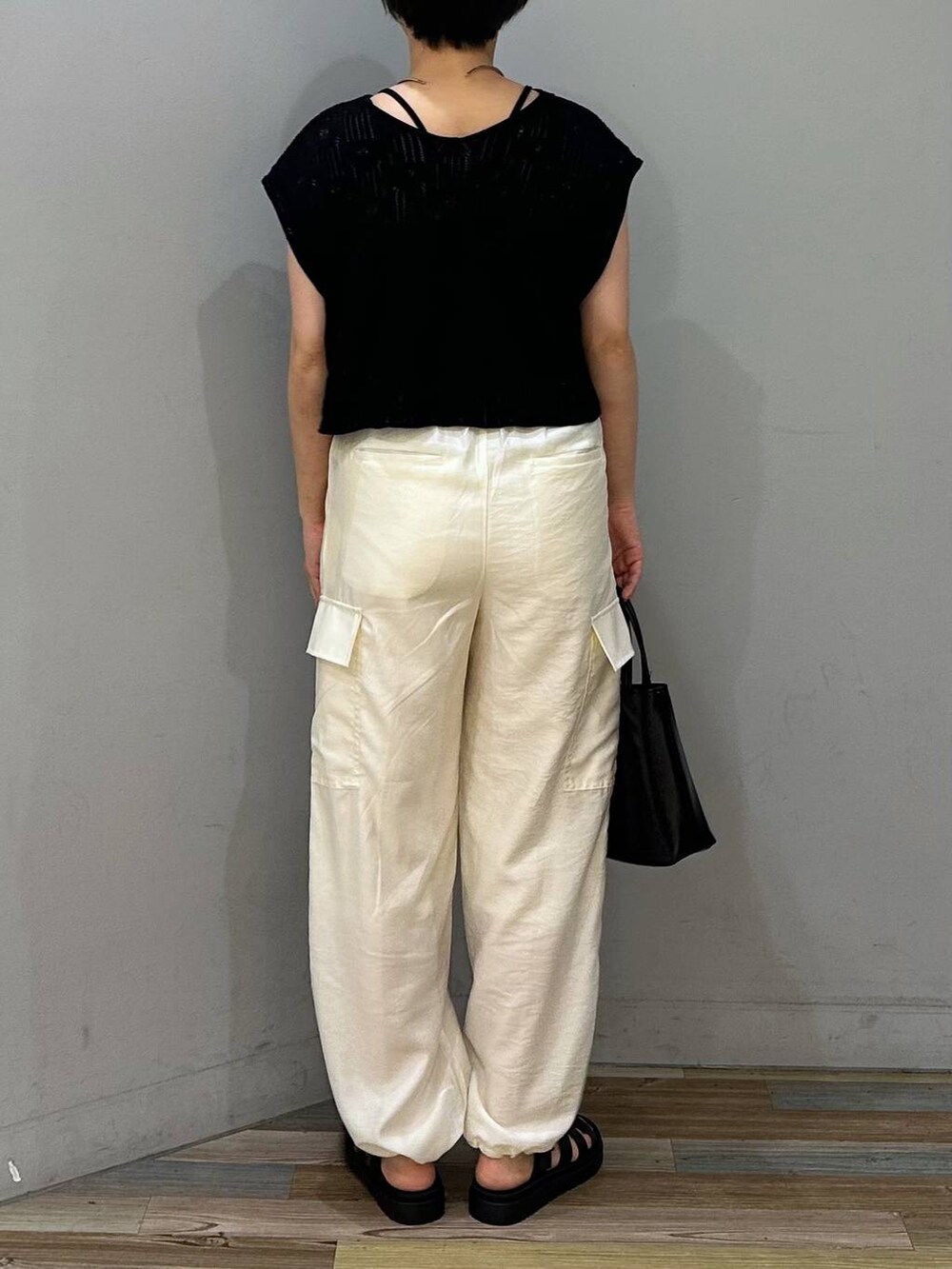 ホワイト系のカーゴパンツ、ブラック系のスニーカー、ブラック系のショルダーバッグを着用したレディースの夏コーディネートの3枚目の写真