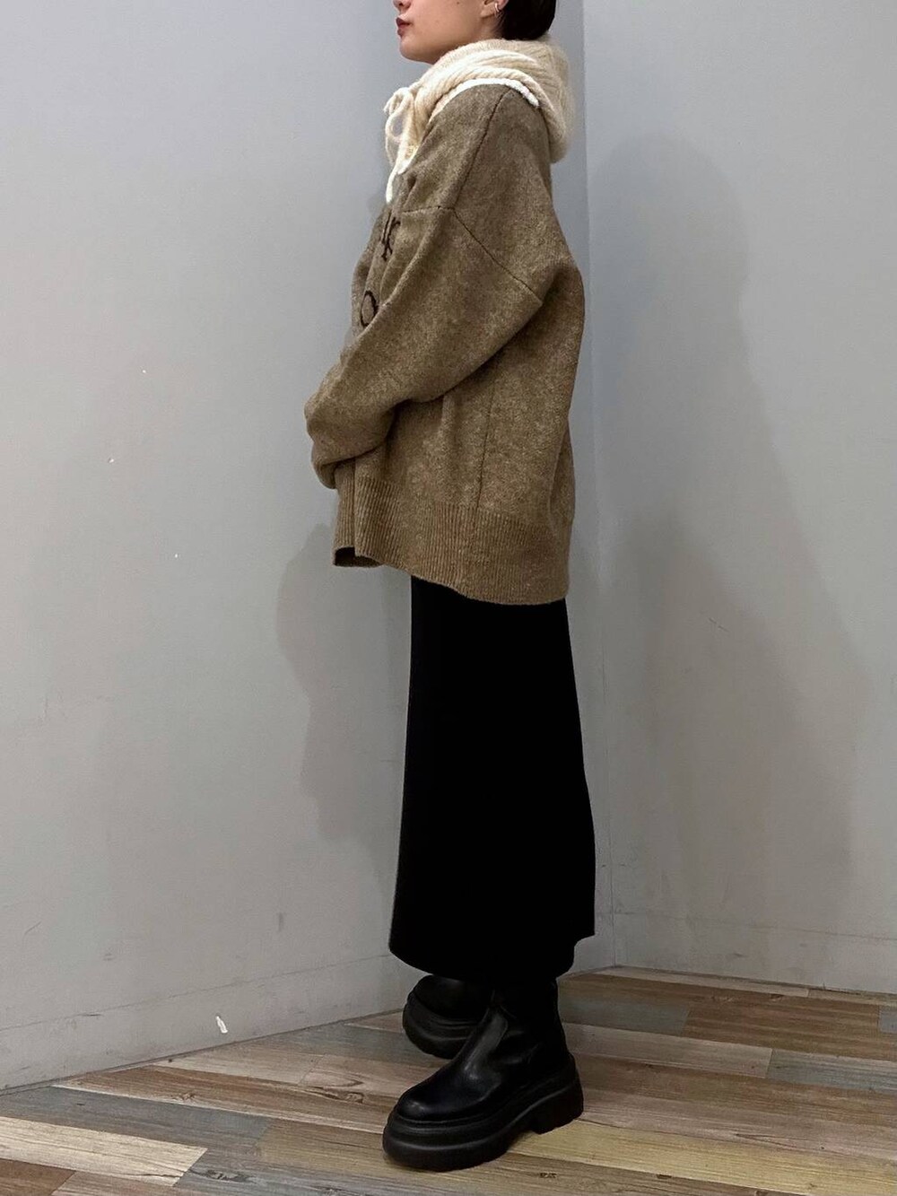 ブラック系のブーツ、ブラック系のスカート、ベージュ系のニット/セーターを着用したレディースの冬コーディネートの2枚目の写真