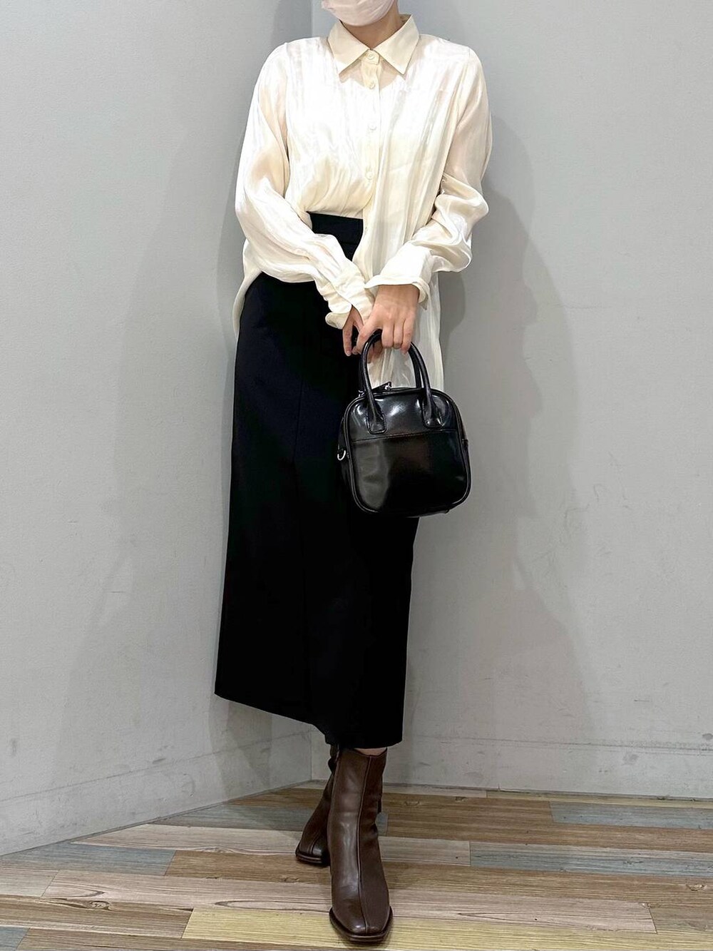 ホワイト系のキャミソール、ブラウン系のパンプス、ブラック系のスカートを着用したレディースの秋コーディネートの4枚目の写真