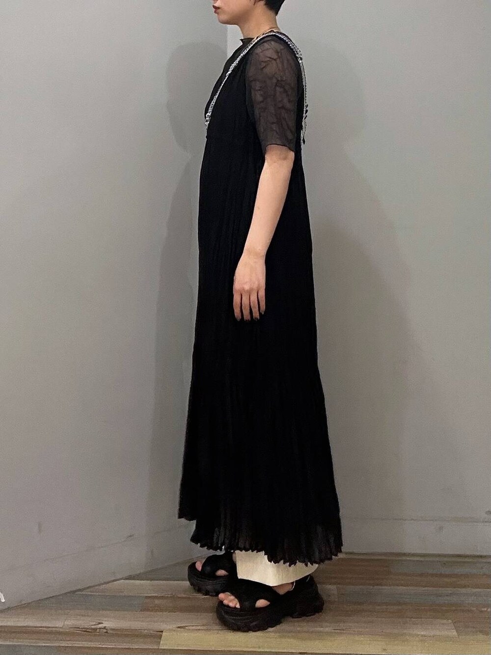 ブラック系のサンダル、ブラック系のワンピース、グレー系のTシャツ/カットソーを着用したレディースの春コーディネートの2枚目の写真