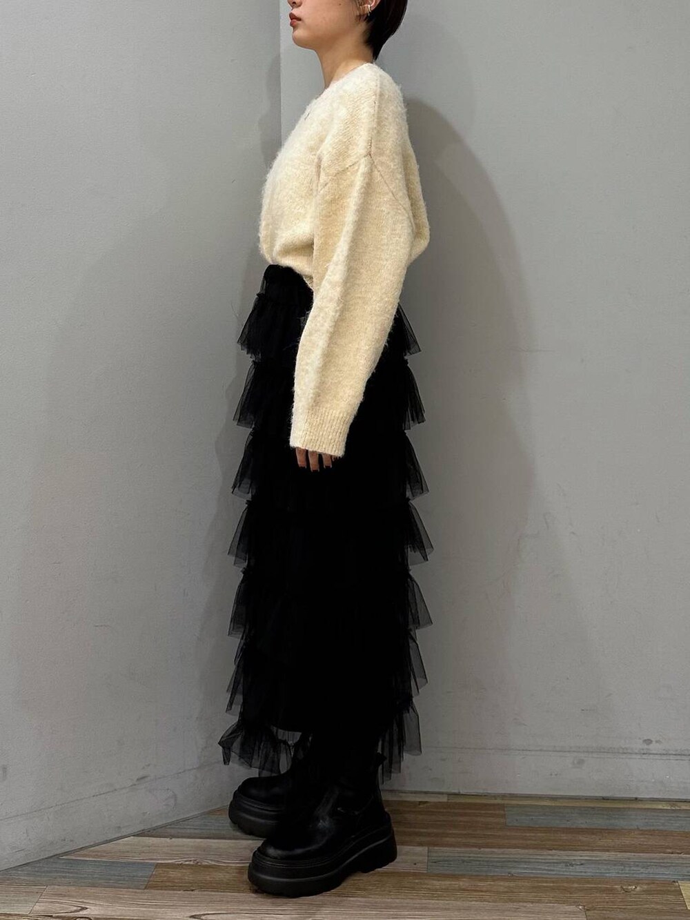 ブラック系のブーツ、ブラック系のスカート、ホワイト系のニット/セーターを着用したレディースの冬コーディネートの2枚目の写真