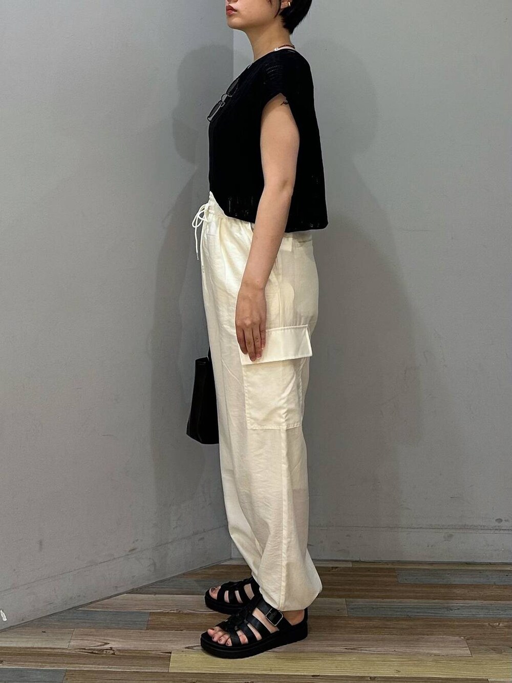 ホワイト系のカーゴパンツ、ブラック系のスニーカー、ブラック系のショルダーバッグを着用したレディースの夏コーディネートの2枚目の写真