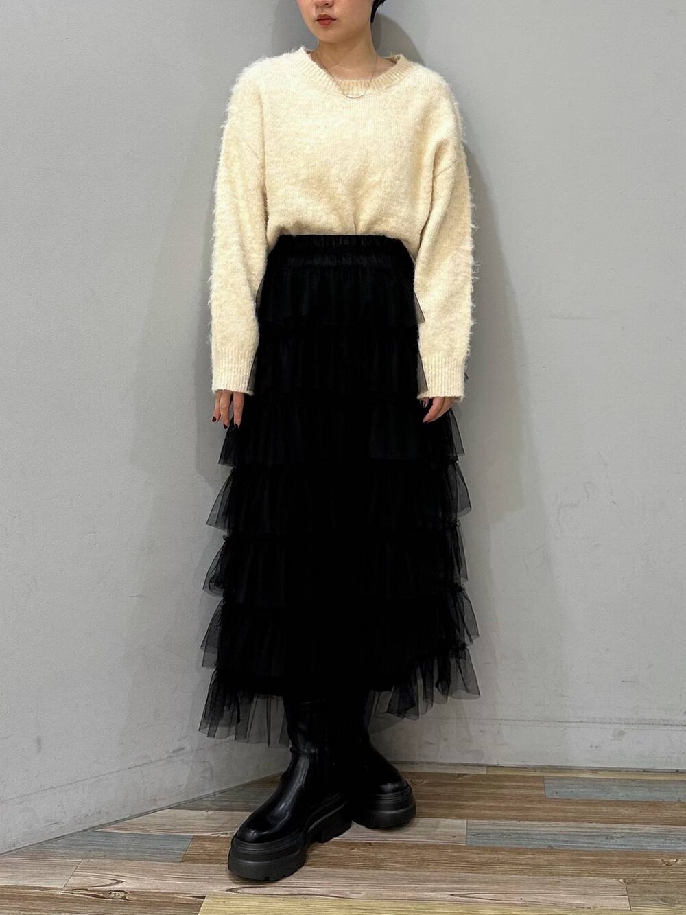ブラック系のブーツ、ブラック系のスカート、ホワイト系のニット/セーターを着用したレディースの冬コーディネートの3枚目の写真