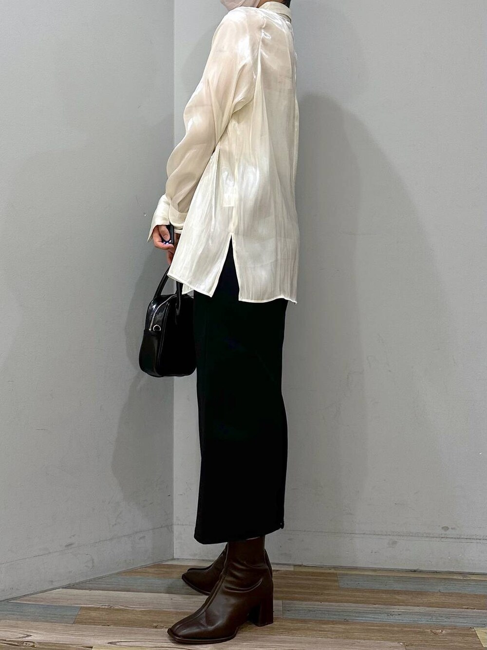 ホワイト系のキャミソール、ブラウン系のパンプス、ブラック系のスカートを着用したレディースの秋コーディネートの2枚目の写真