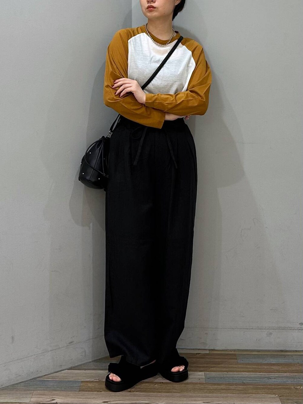 ブラック系のサンダル、ブラック系のショルダーバッグ、グレー系のスラックスを着用したレディースの春コーディネートの2枚目の写真