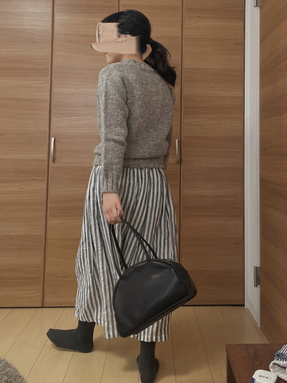 ブルー系のニット/セーター、ホワイト系のスカート、ブラック系のトートバッグを着用したレディースの冬コーディネートの2枚目の写真