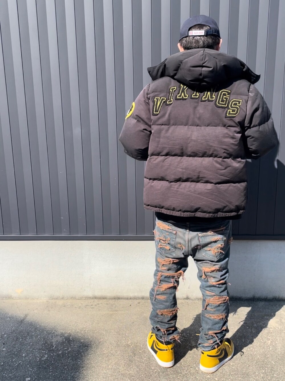 ブラック系のダウンジャケット/コート、ブラック系のTシャツ/カットソー、ブルー系のデニムパンツを着用したメンズの秋コーディネートの3枚目の写真