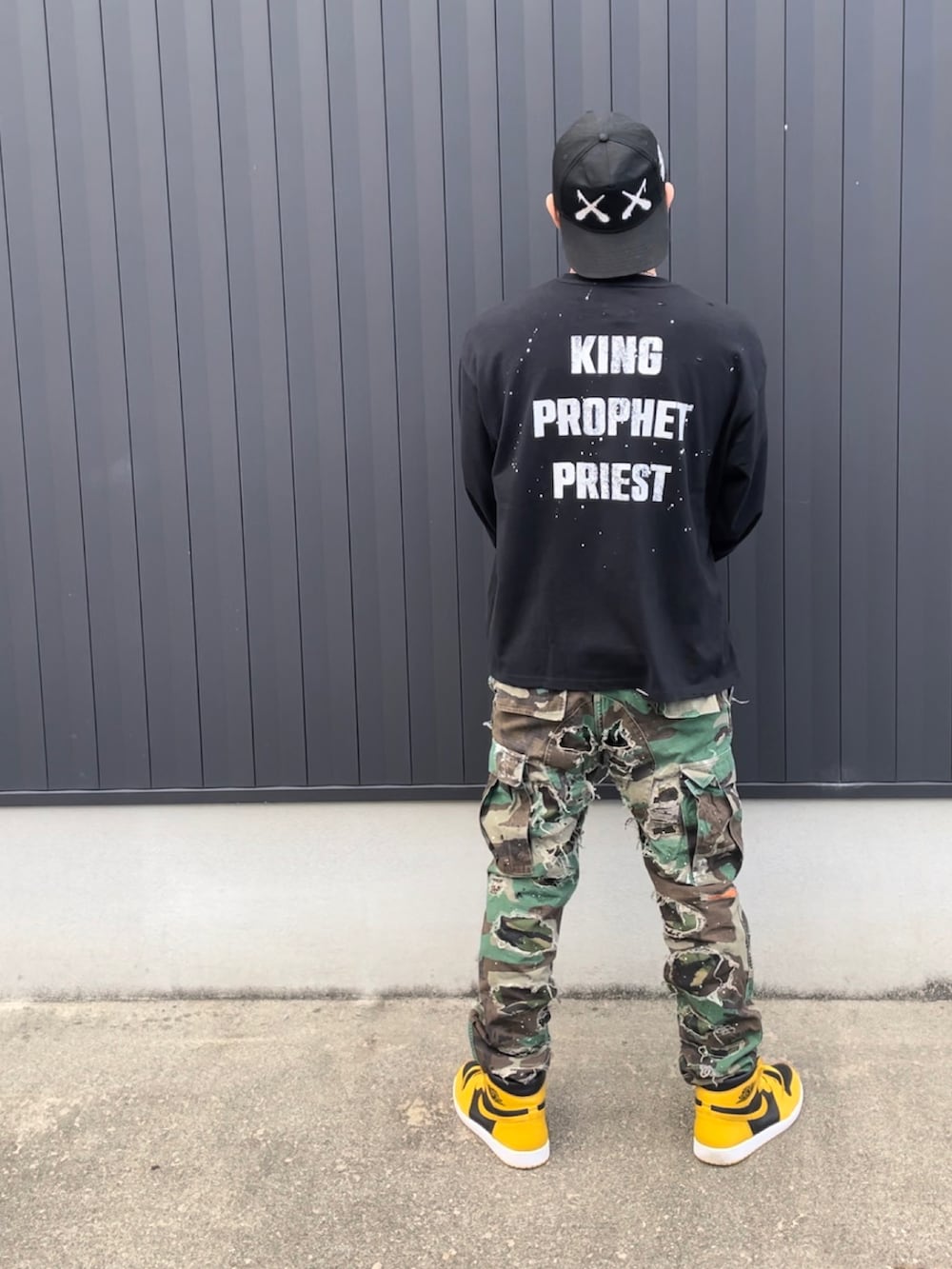 ブラック系のTシャツ/カットソー、イエロー系のスニーカー、グリーン系のパンツを着用したメンズの秋コーディネートの2枚目の写真