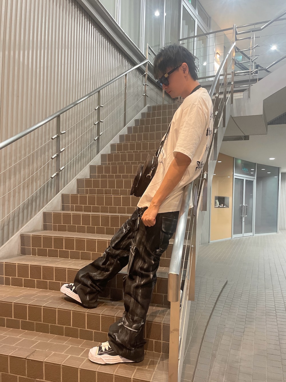 ブラック系のショルダーバッグ、ホワイト系のTシャツ/カットソー、ブラック系のカーゴパンツを着用したメンズの夏コーディネートの3枚目の写真