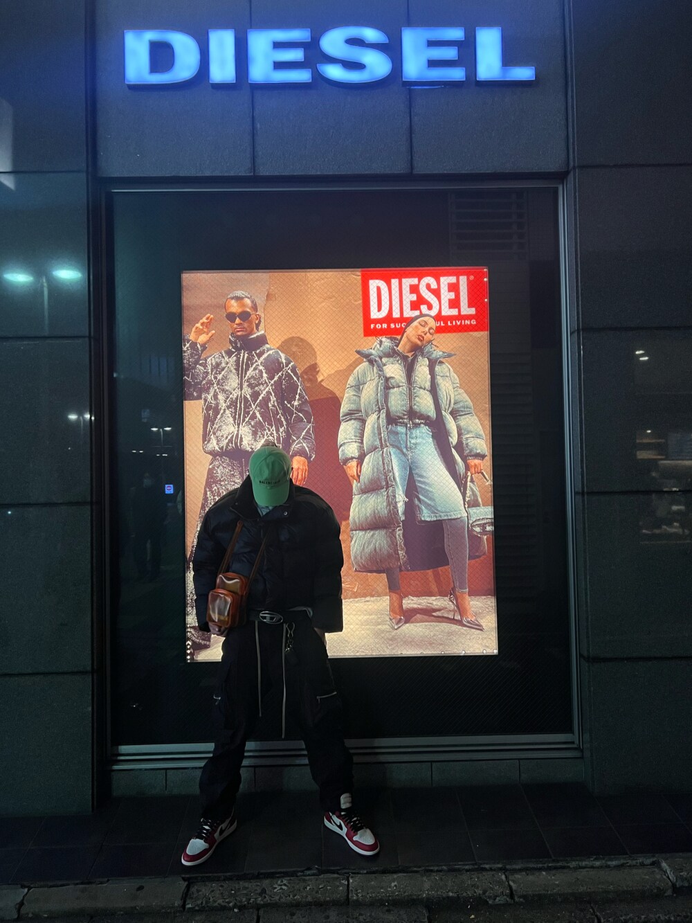 ブラック系のダウンジャケット/コート、オレンジ系のショルダーバッグ、ブラック系のカーゴパンツを着用したメンズの冬コーディネートの2枚目の写真