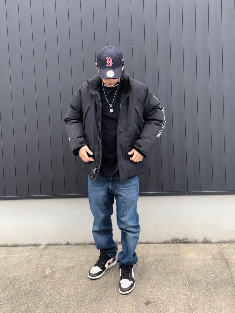 ブラック系のダウンジャケット/コート、ブルー系のデニムパンツ、ブラック系のスニーカーを着用したメンズの秋コーディネートの2枚目の写真