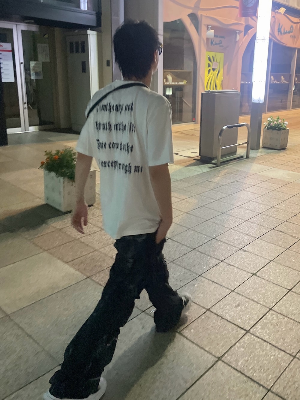 ブラック系のショルダーバッグ、ホワイト系のTシャツ/カットソー、ブラック系のカーゴパンツを着用したメンズの夏コーディネートの5枚目の写真