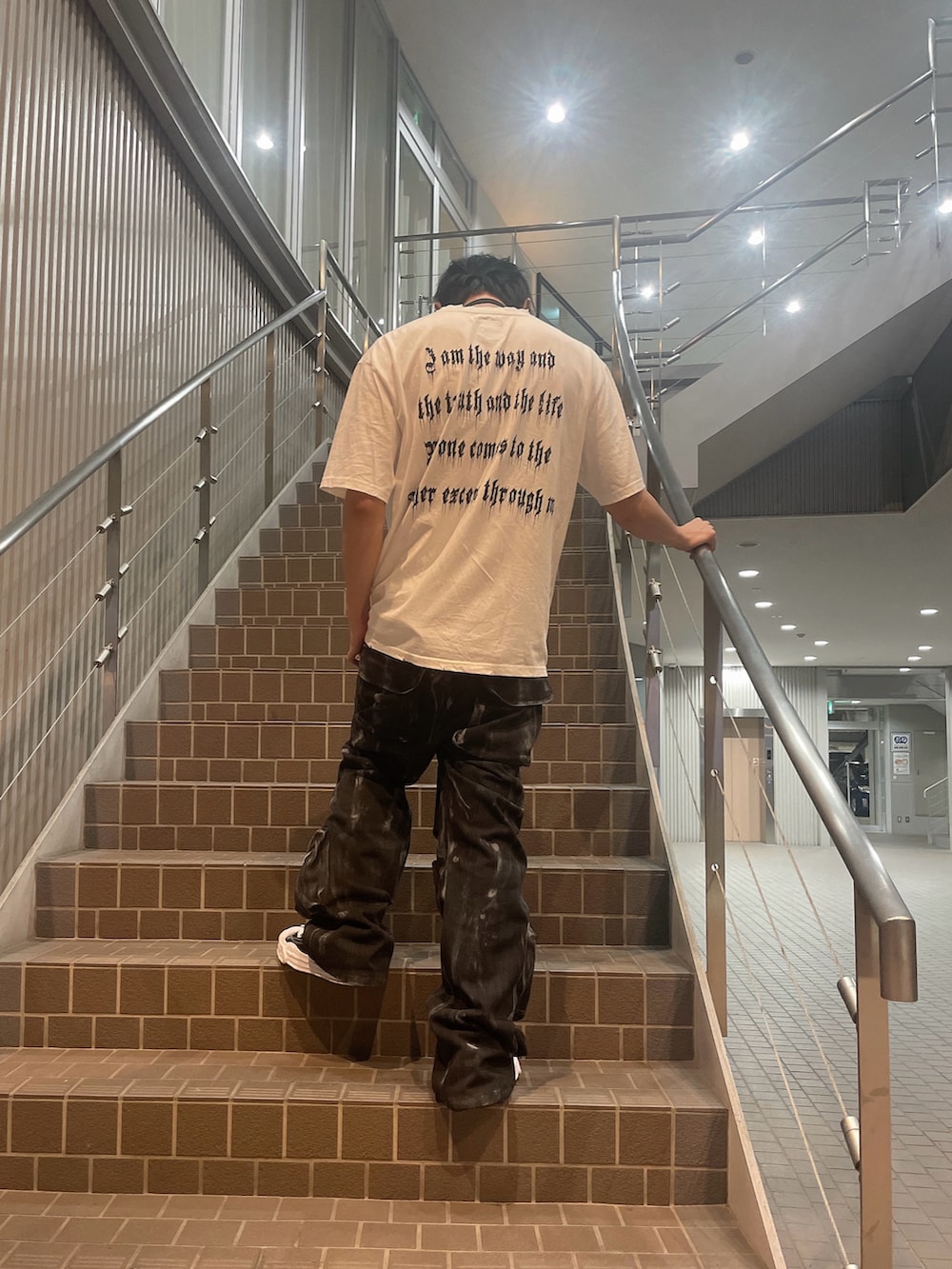 ブラック系のショルダーバッグ、ホワイト系のTシャツ/カットソー、ブラック系のカーゴパンツを着用したメンズの夏コーディネートの2枚目の写真