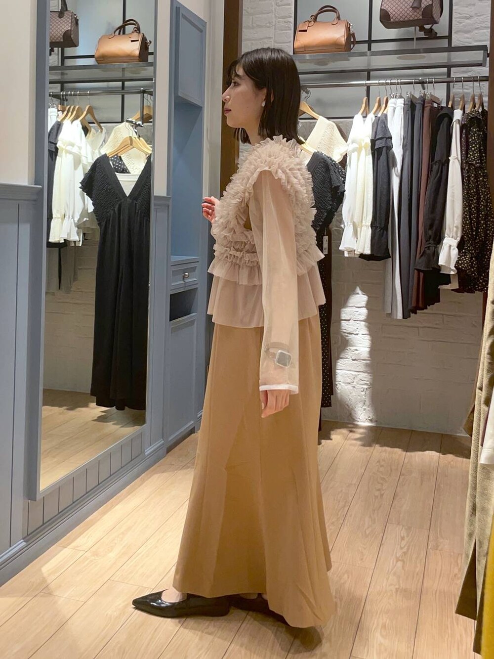 ブラック系のボストンバッグ、ブラック系のパンプス、ベージュ系のワンピースを着用したレディースの秋コーディネートの3枚目の写真