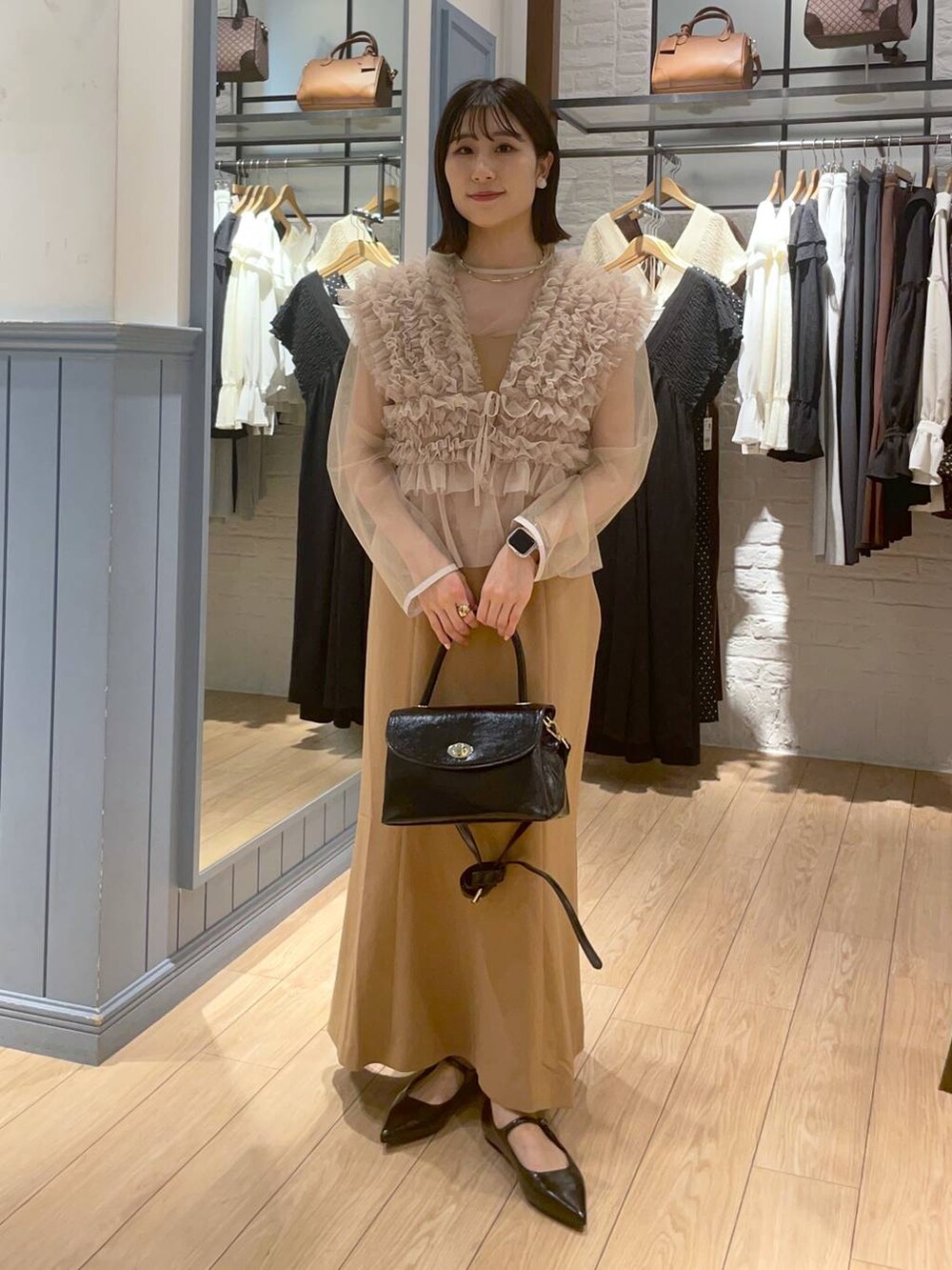 ブラック系のボストンバッグ、ブラック系のパンプス、ベージュ系のワンピースを着用したレディースの秋コーディネートの2枚目の写真