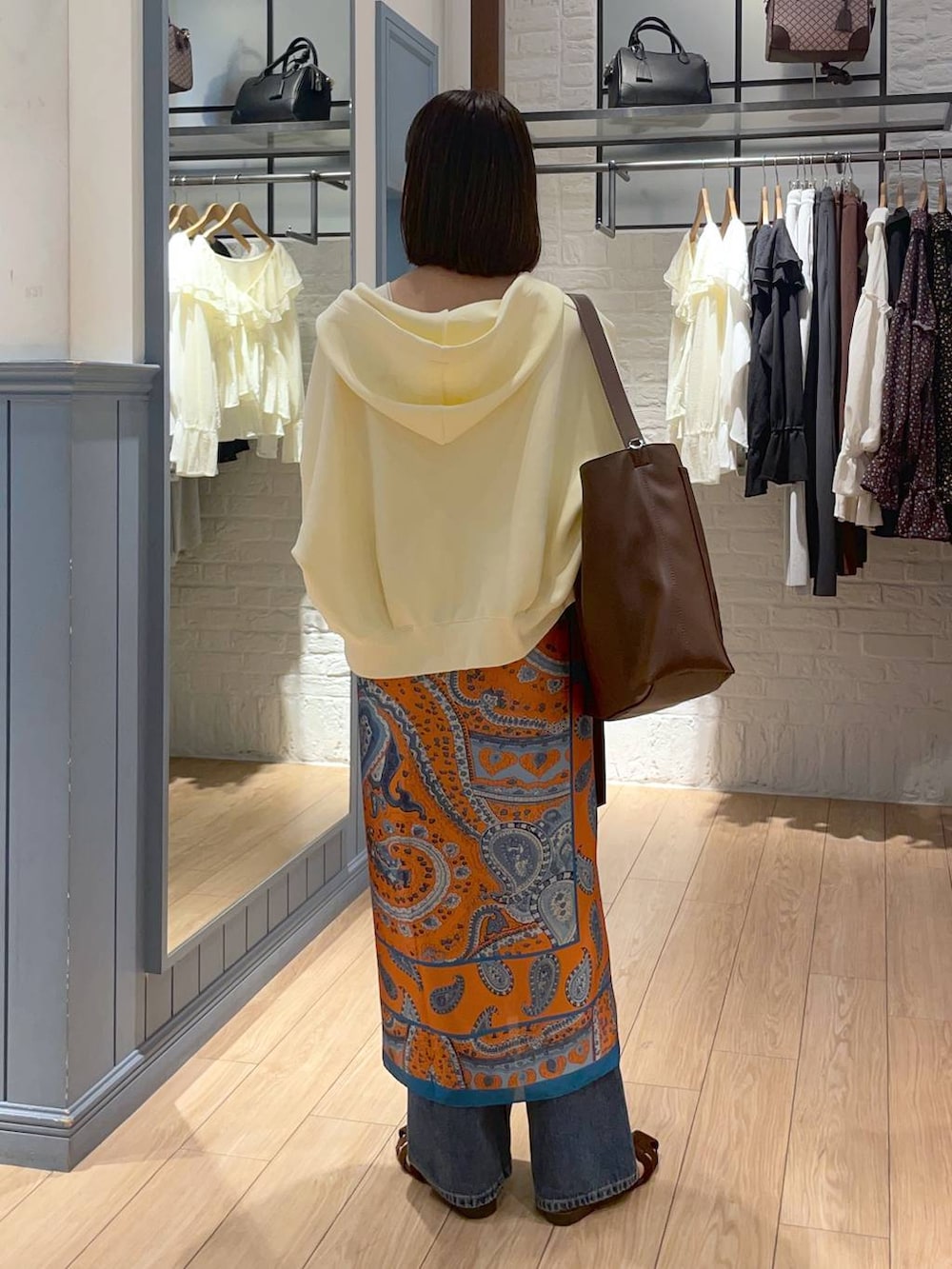 ゴールド系のタンクトップ、ブラウン系のサンダル、ブルー系のデニムパンツを着用したレディースの秋コーディネートの4枚目の写真