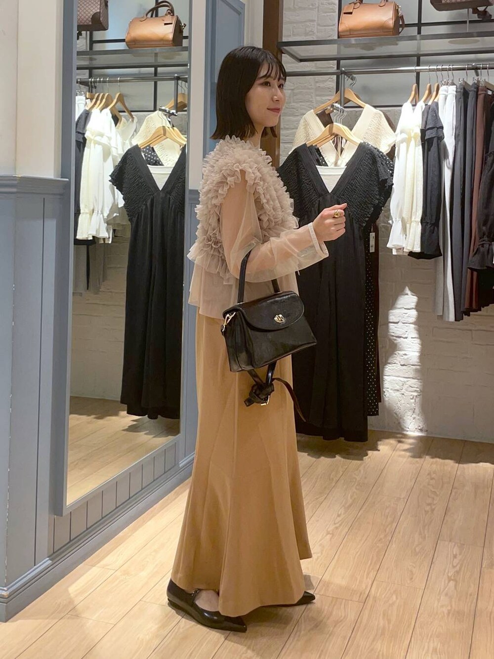 ブラック系のボストンバッグ、ブラック系のパンプス、ベージュ系のワンピースを着用したレディースの秋コーディネートの4枚目の写真