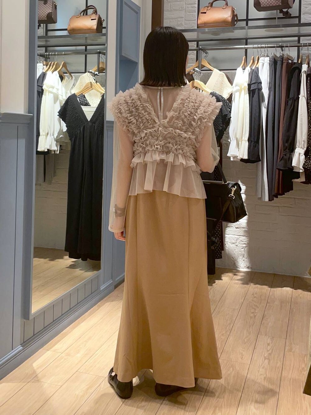 ブラック系のボストンバッグ、ブラック系のパンプス、ベージュ系のワンピースを着用したレディースの秋コーディネートの5枚目の写真