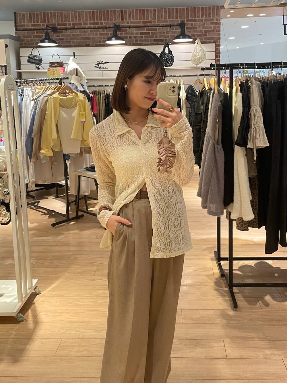 ベージュ系のスラックス、ホワイト系のTシャツ/カットソー、ベージュ系のチョーカーを着用したレディースの夏コーディネートの2枚目の写真