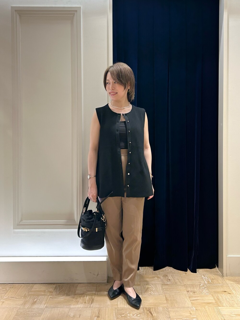 ブラック系のベスト、ブラック系のショルダーバッグ、イエロー系のその他パンツを着用したレディースの秋コーディネートの2枚目の写真