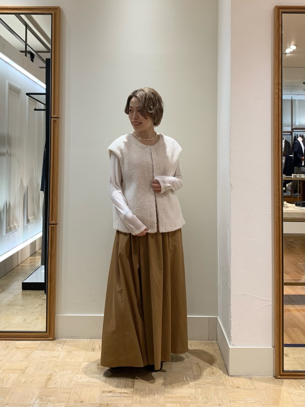 ホワイト系のベスト、ホワイト系のTシャツ/カットソー、イエロー系のスカートを着用したレディースの秋コーディネートの2枚目の写真