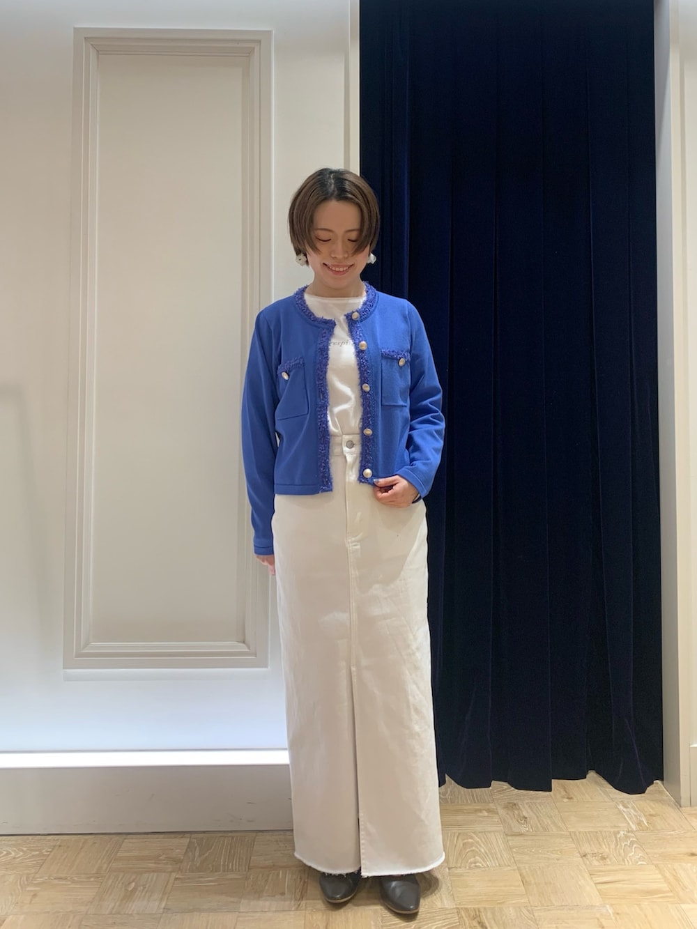 ホワイト系のTシャツ/カットソー、ブルー系のカーディガン/ボレロ、ホワイト系のデニムスカートを着用したレディースの春コーディネートの2枚目の写真