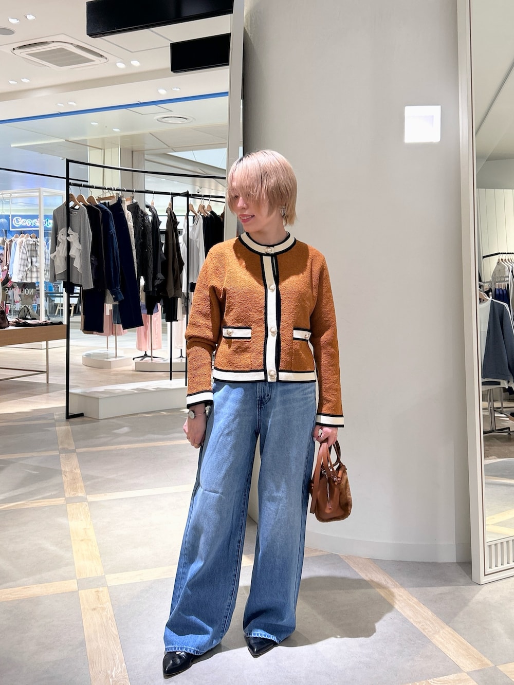 イエロー系のカーディガン/ボレロ、ブルー系のデニムパンツ、イエロー系のショルダーバッグを着用したレディースの秋コーディネートの2枚目の写真