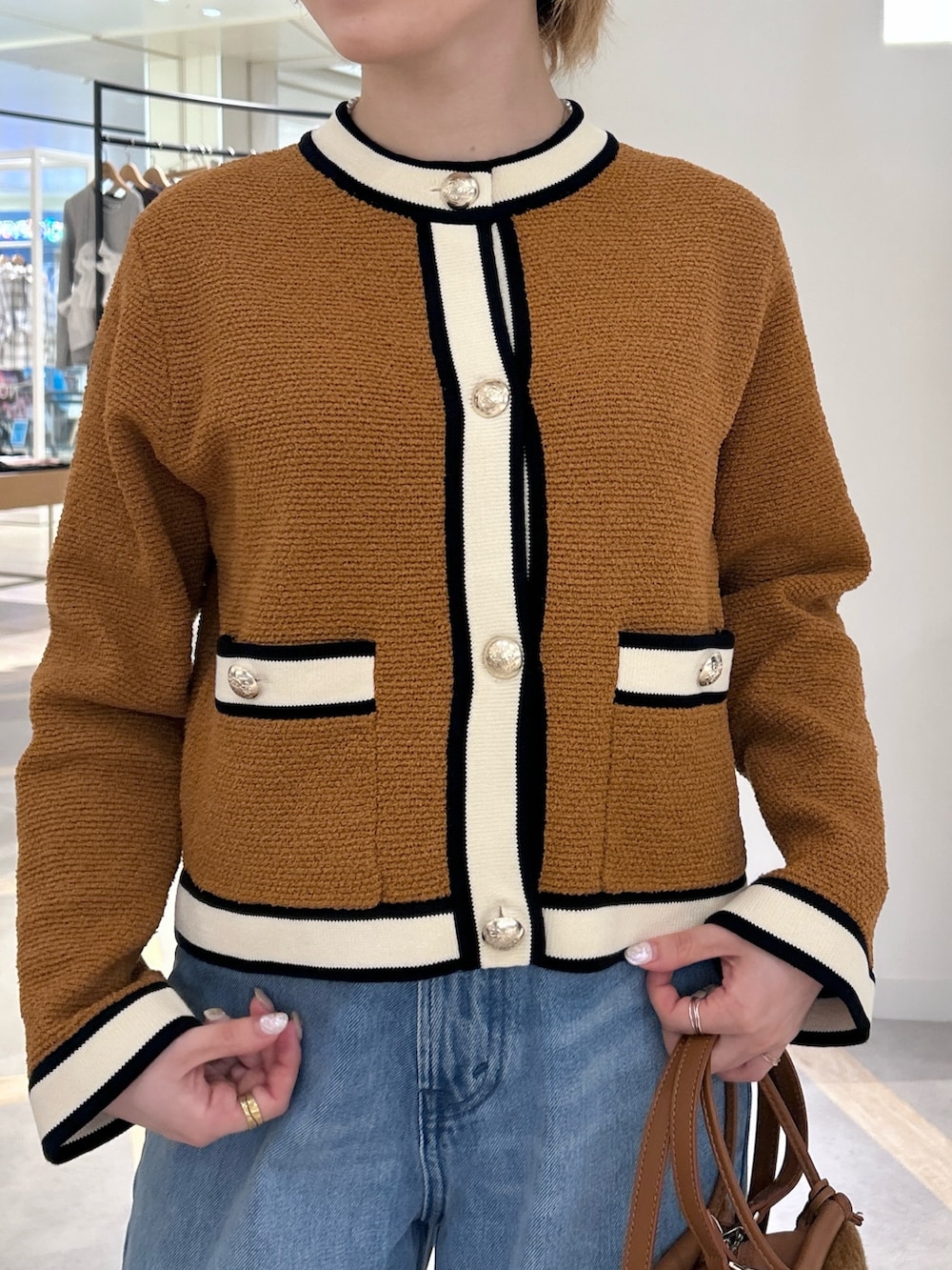 イエロー系のカーディガン/ボレロ、ブルー系のデニムパンツ、イエロー系のショルダーバッグを着用したレディースの秋コーディネートの3枚目の写真